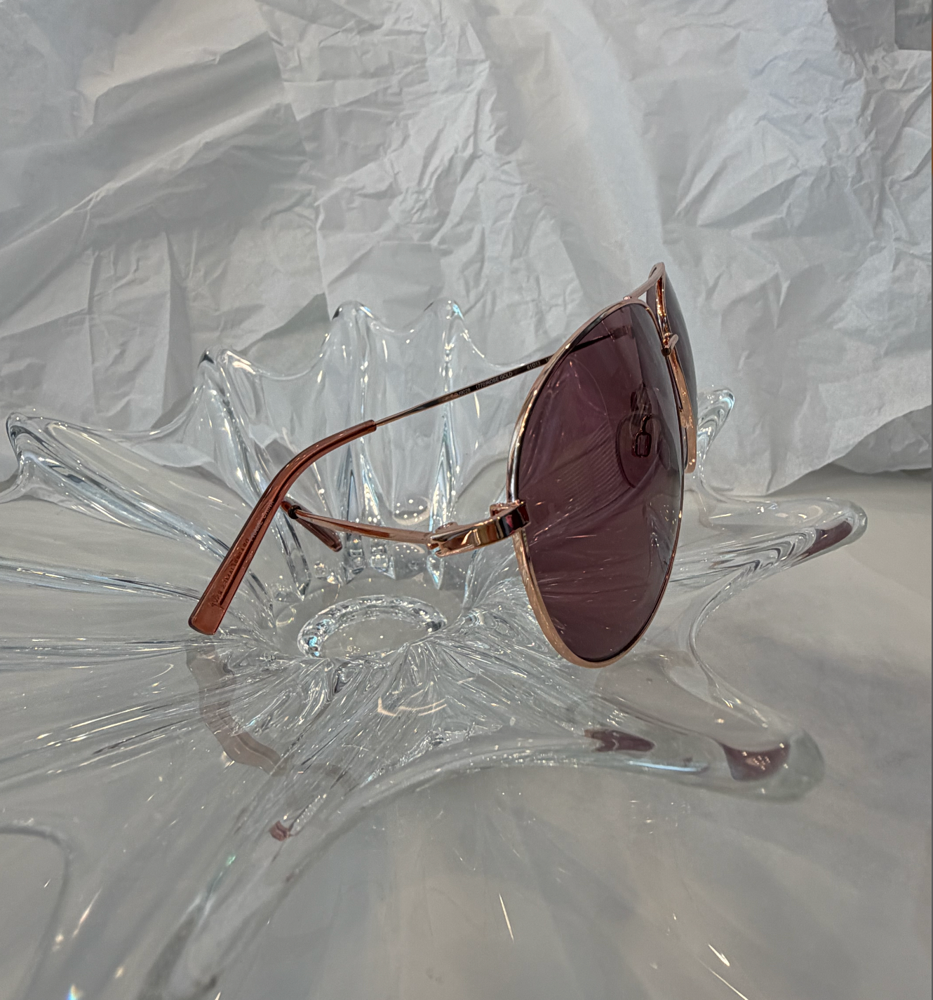Draper James DJ9028 rose gold aviator sunglasses top view on crystal display