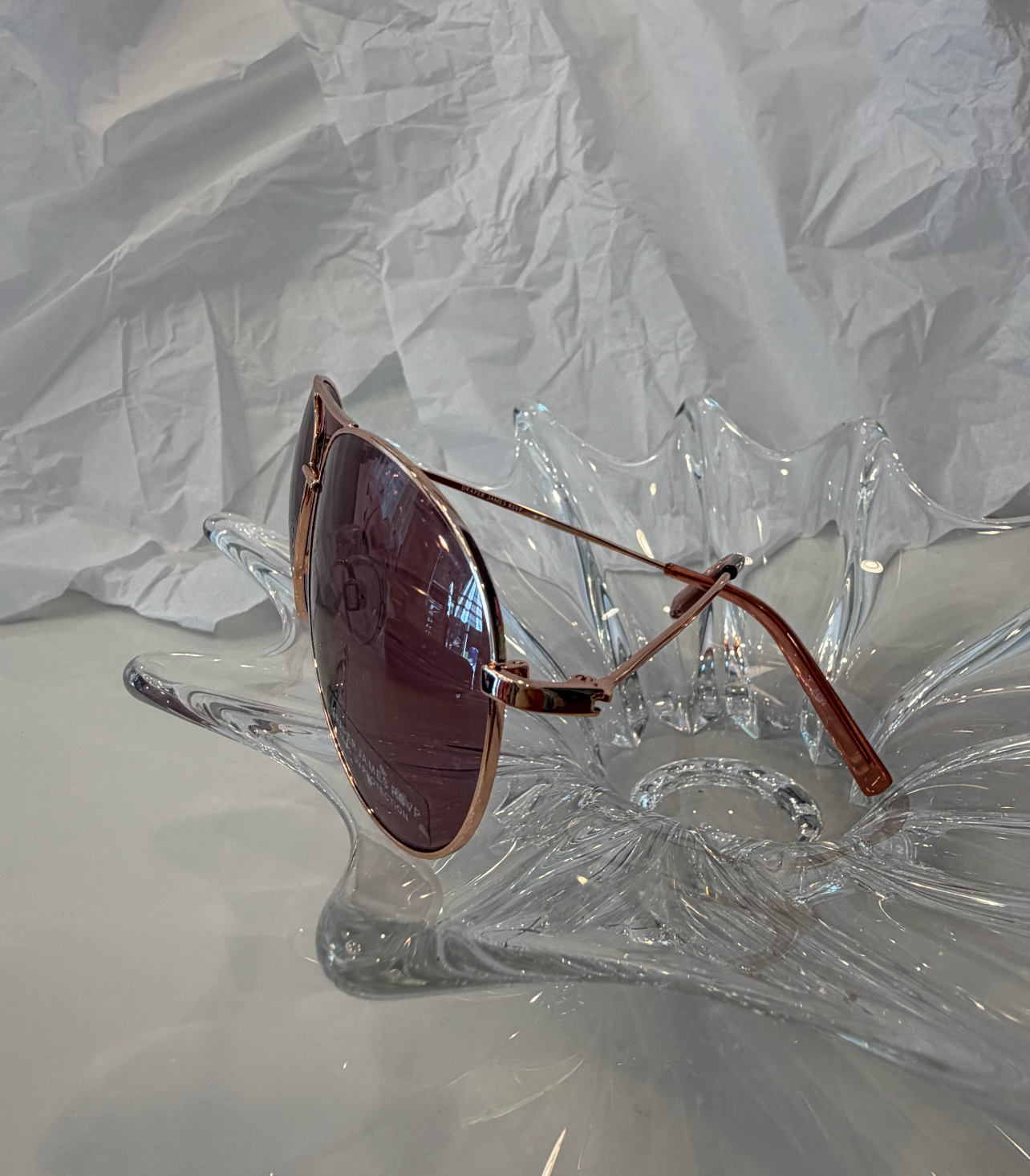 Draper James DJ9028 rose gold aviator sunglasses side view on crystal display