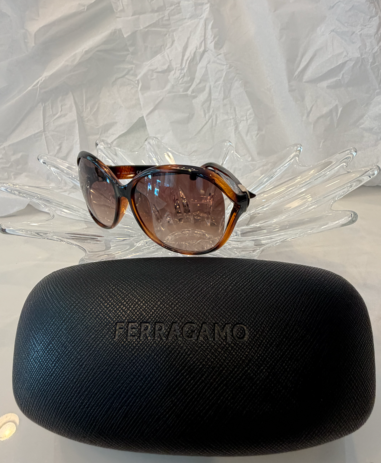 Salvatore Ferragamo oversized butterfly sunglasses side angle view on crystal display showing tortoise frame and Ferragamo script logo