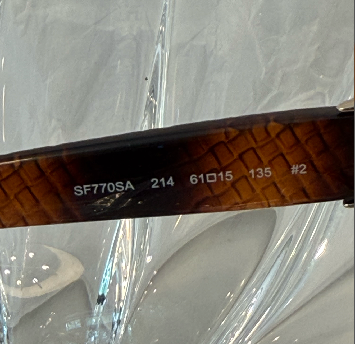 Salvatore Ferragamo silver hinge plate close-up showing Ferragamo script logo engraving