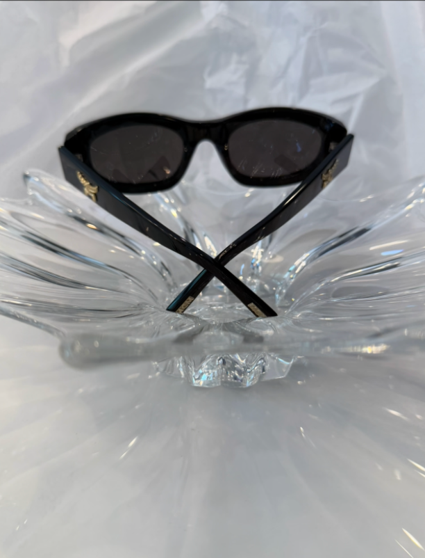MCM gold Laurel logo hardware close-up on black acetate temple