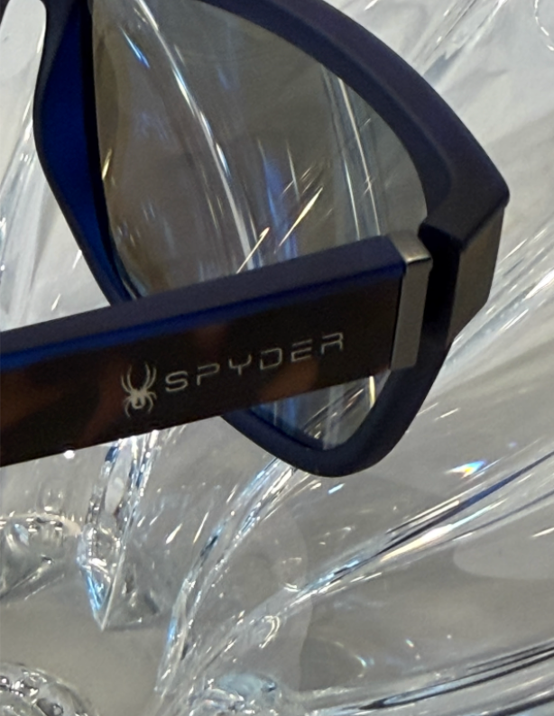 Spyder spider logo and SPYDER branding close-up on dark navy temple