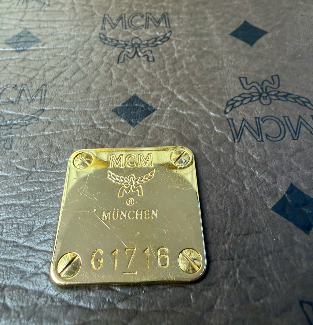 MCM gold-stamped magnetic snap closure detail on Visetos canvas